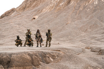 Special Forces Team Standing Together in Desert Mountain Terrain – Tactical Soldiers in Full Gear...