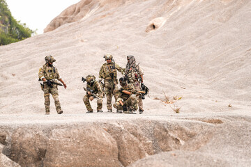 Special Forces Team Standing Together in Desert Mountain Terrain – Tactical Soldiers in Full Gear...
