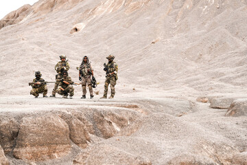 Special Forces Team Standing Together in Desert Mountain Terrain – Tactical Soldiers in Full Gear...