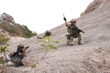 Special Forces Team During Military Operation on Rocky Slope – Soldier Holding Red Flare and...