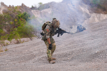 Special forces soldier uses a radio during a tactical operation while red flare smoke spreads...