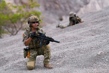 Special forces soldier uses a radio during a tactical operation while red flare smoke spreads...
