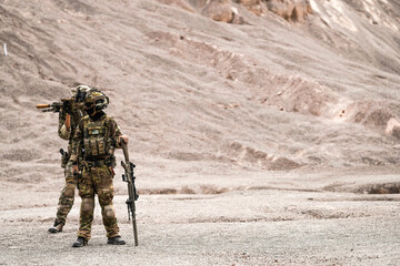A group of special forces soldiers conduct a briefing in a rugged desert mountain environment....