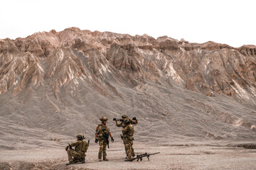 A group of special forces soldiers conduct a briefing in a rugged desert mountain environment....