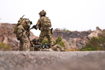 Three Soldiers in Combat Gear Holding Tactical Positions on Rocky Terrain – Realistic Military...