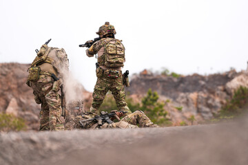 Fototapeta premium Three Soldiers in Combat Gear Holding Tactical Positions on Rocky Terrain – Realistic Military Operation Scene with Teamwork, Readiness, and Strategic Communication