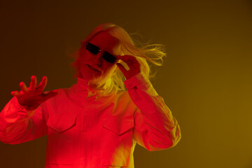 Stylish model in vibrant colors, showcasing modern fashion with long hair and sunglasses against a warm gradient background, creating a dynamic atmosphere and artistic expression