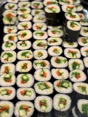 Variety of Freshly Prepared Sushi Rolls Beautifully Arranged on Display for Patrons. Exquisite and vibrant array of sushi rolls brilliantly showcasing various ingredients with artistic presentation