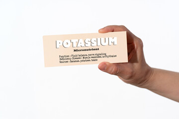 A hand holding a paper displaying key facts about Potassium or Kalium as an essential micronutrient...