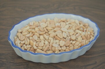 Mani tostado en recipiente blanco sobre mesa de madera