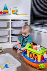 A baby sits on the floor, happily playing with toys