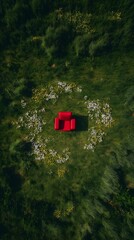 Naklejka premium Red Couch in Green Grass: A Vibrant Outdoor Seating Area Surrounded by Flowers for a Picturesque Relaxation Space with a Modern, Bohemian Flair