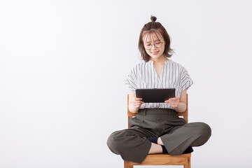 椅子に座りタブレットを使う若い女性
