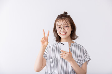 スマートフォン片手にブイサインをする女子大生
