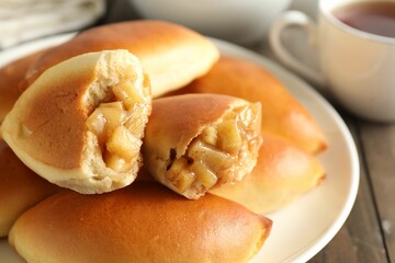 Tasty baked patties with apples on wooden table, closeup