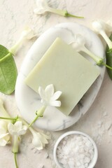 Bar of soap, sea salt and jasmine flowers on light table, flat lay
