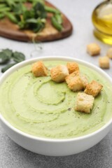 Tasty pea cream soup with croutons served on grey table, closeup