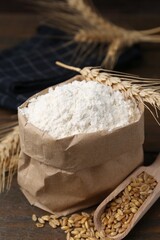 Wheat flour, grain and spikes on wooden table, closeup