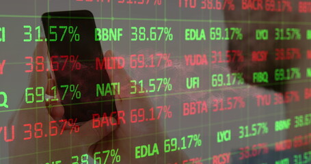 Holding smartphone with left hand in office, displaying stock data on transparent panel, copy space