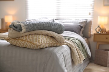 Comfortable bed with soft linens and blankets in room, closeup. Home textile