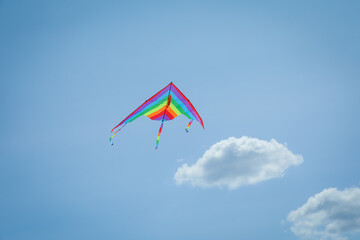Colorful kite flying in blue sky, low angle view