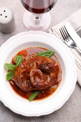 Traditional ossobuco dish with beef steak served on grey table, flat lay