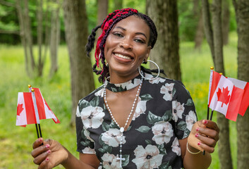 Happy African American Woman Celebrating Canada Day July 1st with Red Maple Leaf Flags