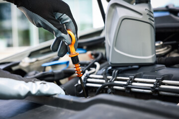 Worker checking motor oil level in car with dipstick, closeup