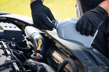 Worker checking motor oil level in car with dipstick, closeup
