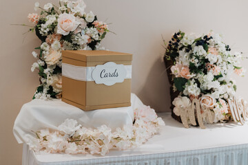 Gold wedding card box wrapped with white ribbon labeled “Cards” on draped table with blush...