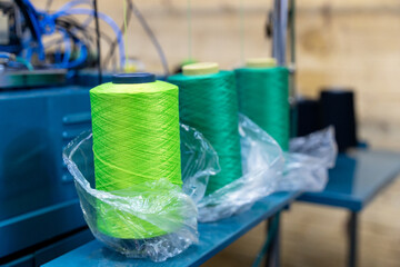 Close-up of vibrant green thread spools on a machine in a textile factory. showcasing industrial textile equipment and modern manufacturing processes.