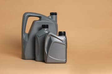 Motor oil in plastic canisters on beige background, space for text