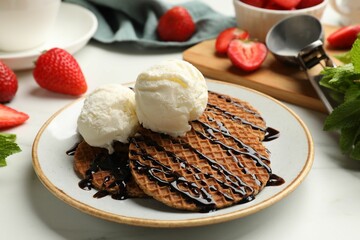 Tasty Dutch waffles (stroopwafels) with ice cream and chocolate sauce on white table, closeup