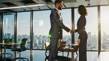 Low-angle shot of two professionals shaking hands in a modern office with city view, capturing a dynamic and collaborative business video concept.