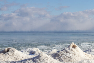 Lake with snow hills and puffy clouds on horizon