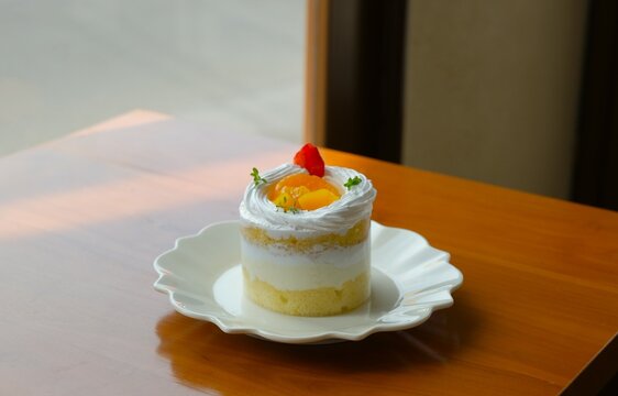 Beautiful mini cake on white plate. Decorated cake with slices of oranges, peach and strawberry on top. Dessert for party, celebration, festive, and Eid mubarak