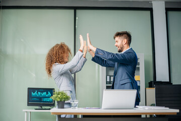 Happy business team cheering in office after project success. Celebration, teamwork victory, achievement