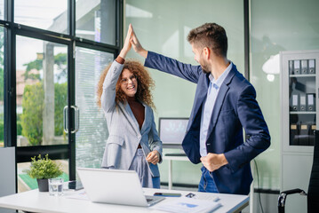 Happy business team cheering in office after project success. Celebration, teamwork victory,...
