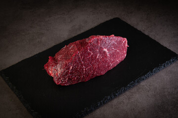 Raw beef steak on a black slate board