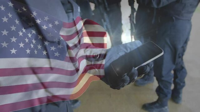 Tight shot opening gloved operator rotating lit phone for briefing while flag overlay intensifying