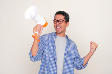 Adult Asian man clenched fist showing enthusiastic expression when announce good news using...