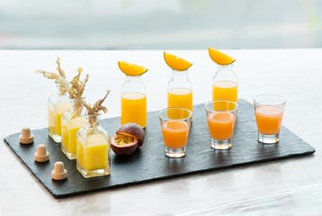 Fresh juice tasting flight with orange & tropical flavors on slate board. Premium cold-pressed...