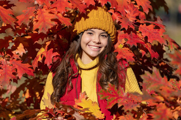 Child girl in autumn fall park outdoor, kids fun face. happy teen girl portrait in hat at autumn leaves on natural background