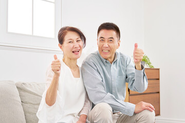 シニアの夫婦　グッドサイン　リビング
