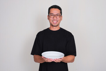 Adult Asian man smiling while holding empty dining plate