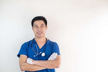 Portrait of a confident Asian male nurse wearing blue medical scrubs standing with arms crossed and...
