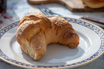 Italian breakfast, fresh baked butter croissant with sugar, served outdoor in sunny day