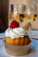 French cuisine, fresh baked baba au rum cake with chantilly cream, sweet dessert with rum and glasses of champagne wine close up