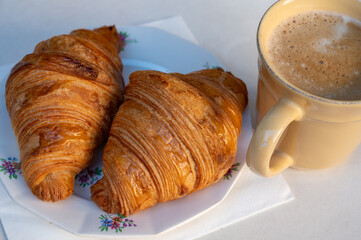 Fresh baked two buttered croissants served with cup of coffee in restaurant for continental or...