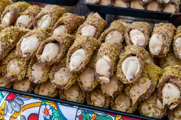Homemade sweet pastry cannolo sfoglie filled with almond, pistachio, lemon, vanilla, chocolate cream on food market in Palermo, Sicily, Italy
